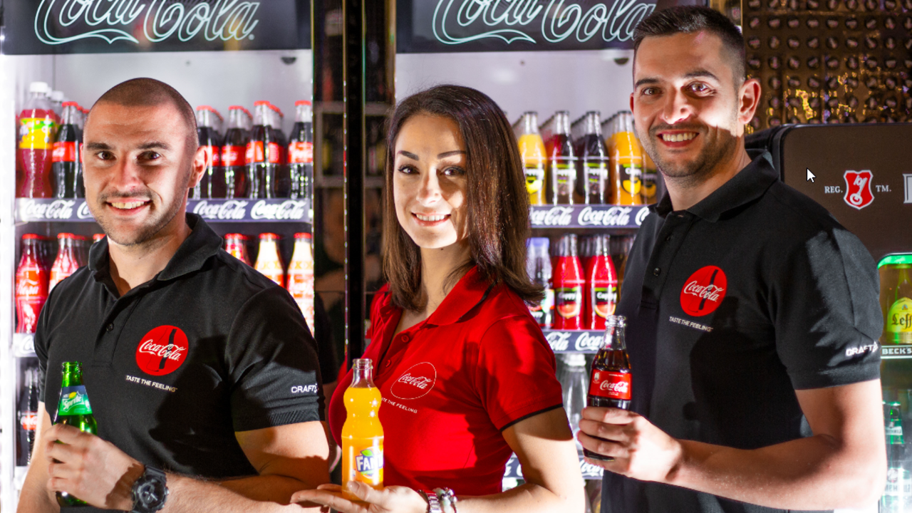 troje ljudi stoji sa Coca-Colinim proizvodima